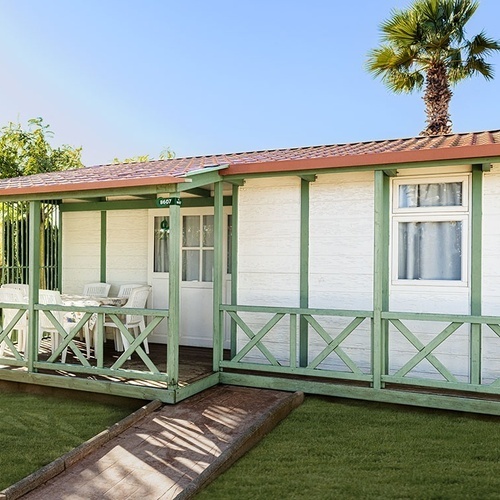 una pequeña casa de madera con una mesa y sillas en el porche
