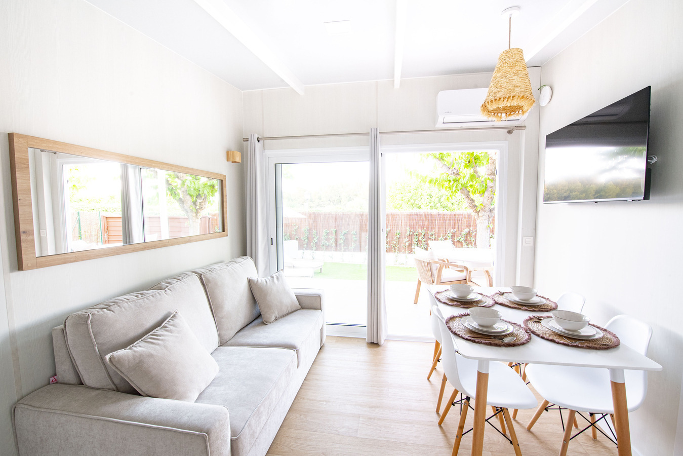 Salon lumineux avec canapé, table à manger et vue sur jardin, idéal pour votre séjour Creixell camping & family resort.