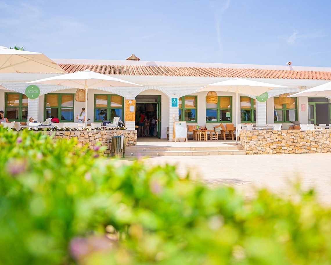 un edificio blanco con una puerta verde y un letrero que dice ' abierto '