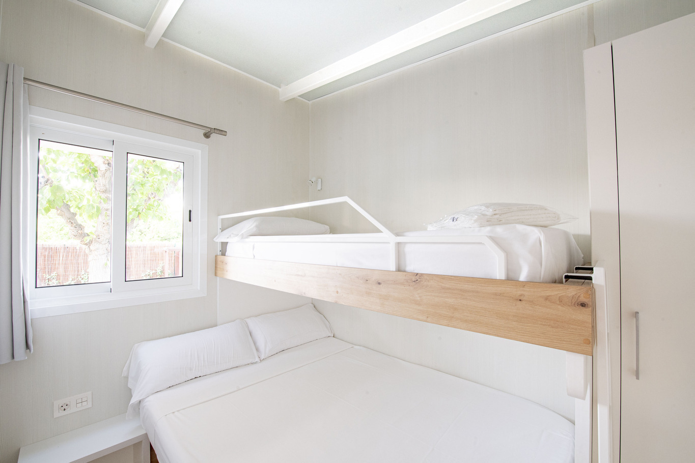Chambre de Creixell camping & family resort avec lits superposés, fenêtre et armoire blanche.