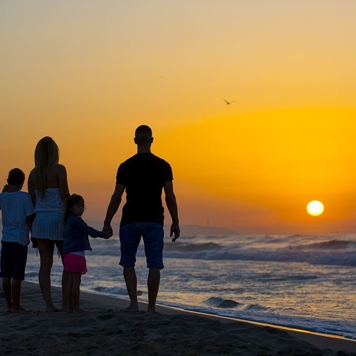 una familia camina por la playa al atardecer