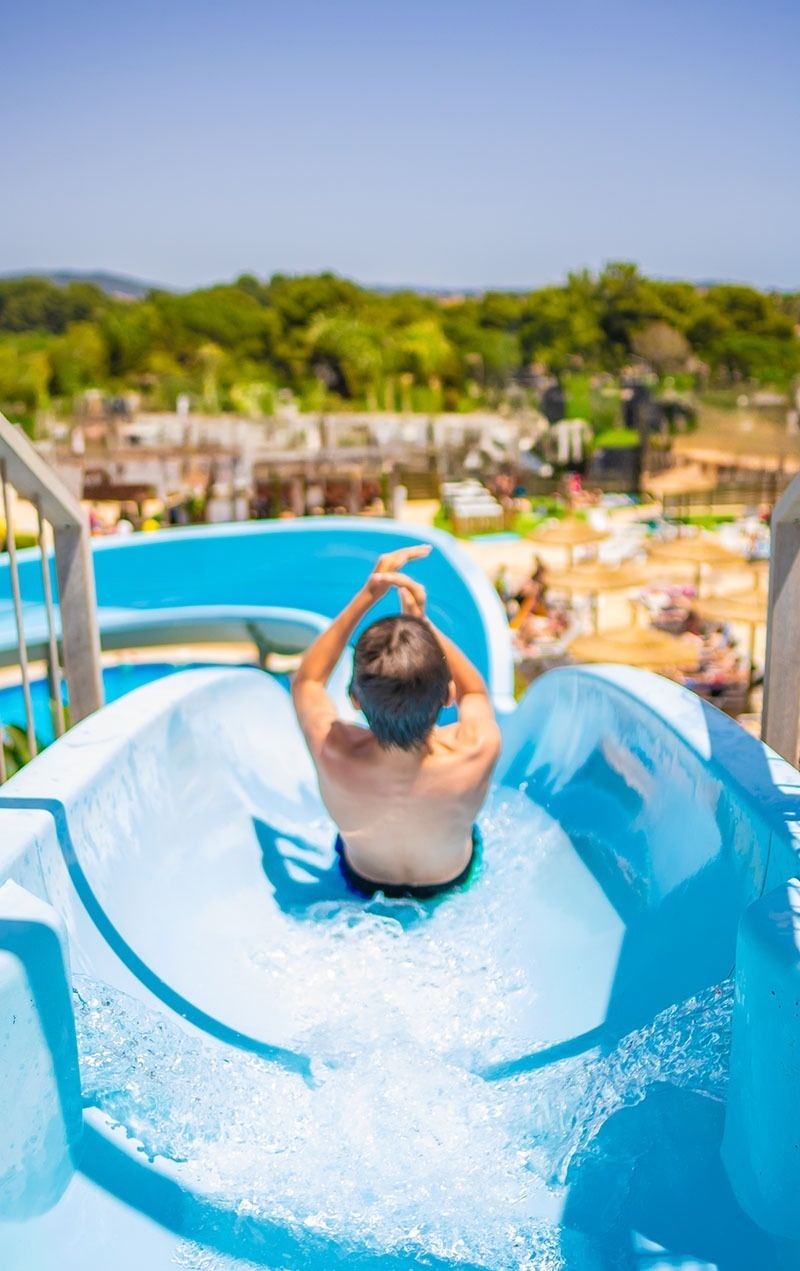 un niño se desliza por un tobogán azul en una piscina