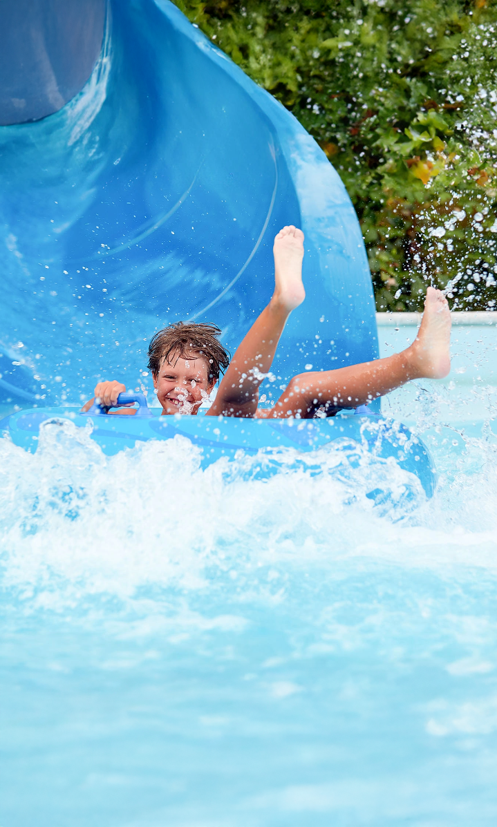un niño se desliza por un tobogán azul en una piscina