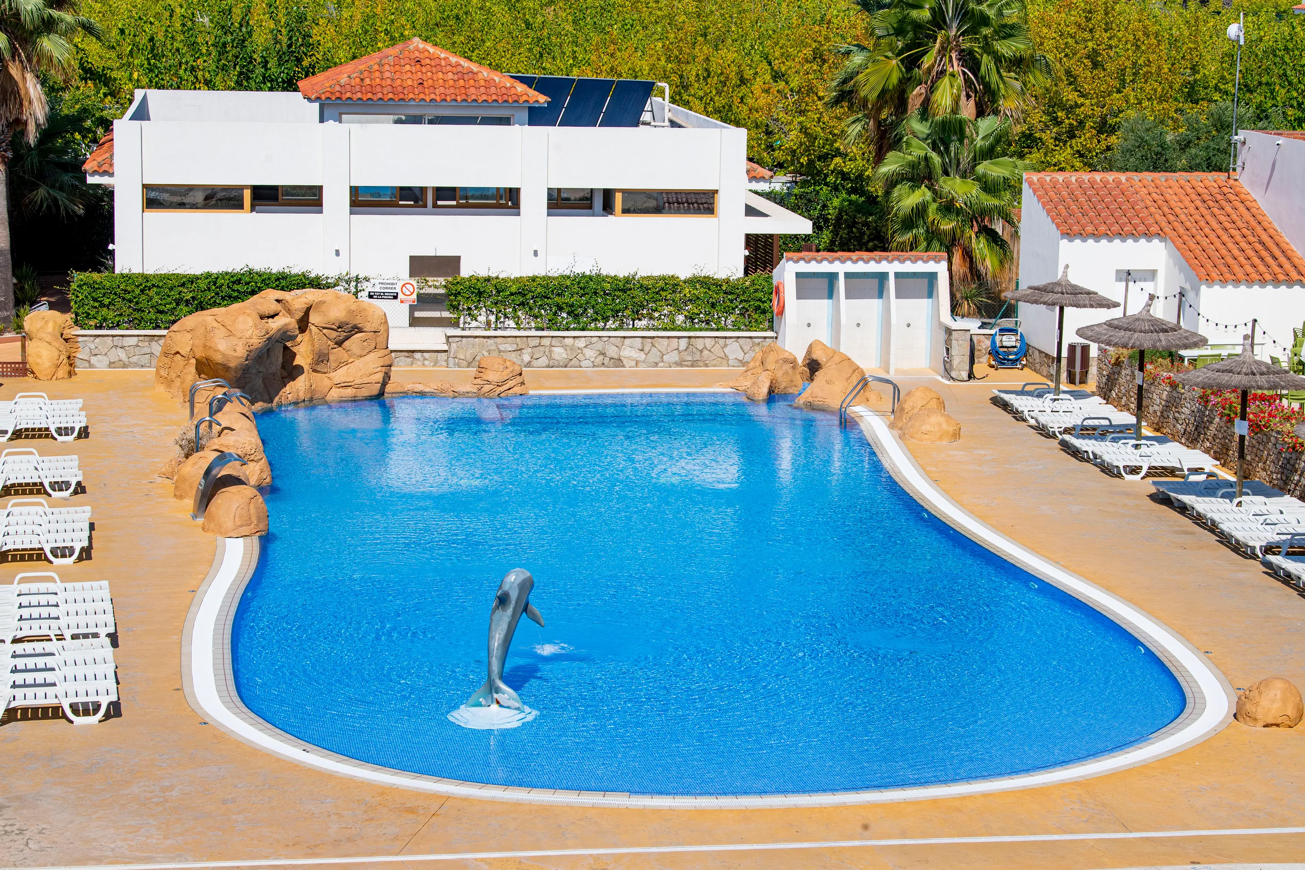 Fantàstica piscina a l'aire lliure amb ampolles i detall de dofí, ideal per a Creixell Camping & Family Resort amb sol.