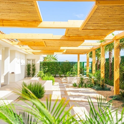 un patio con una pérgola de madera y palmeras