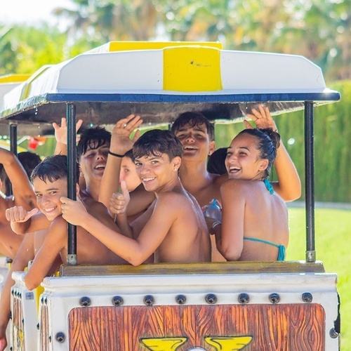 un grupo de niños y niñas están sentados en un tren y dando pulgares hacia arriba