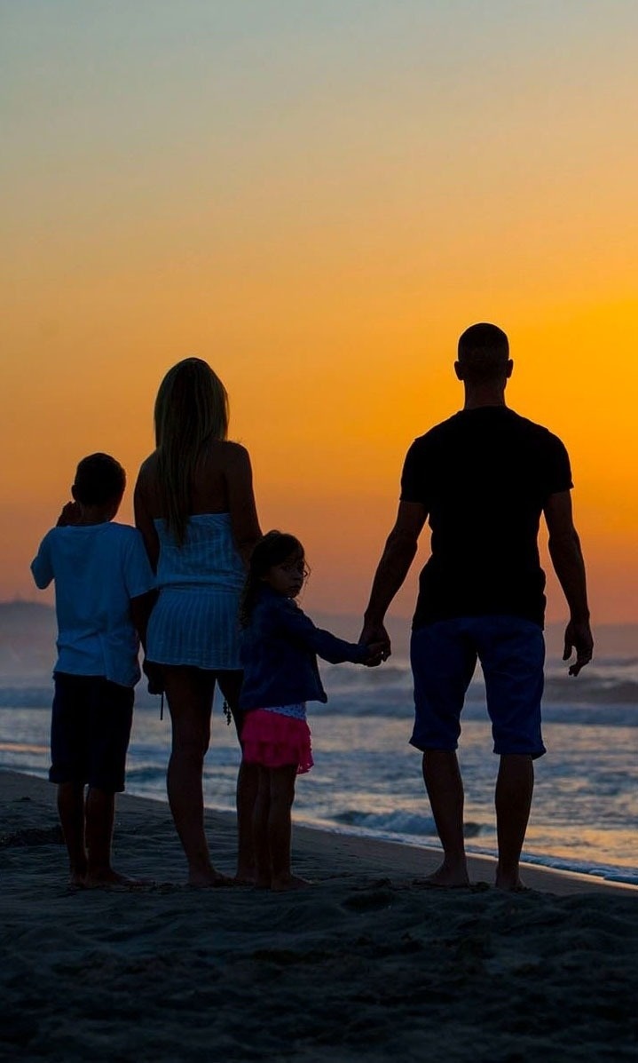 una familia se para en la playa al atardecer