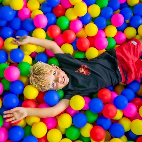 un niño acostado en un montón de bolas de colores