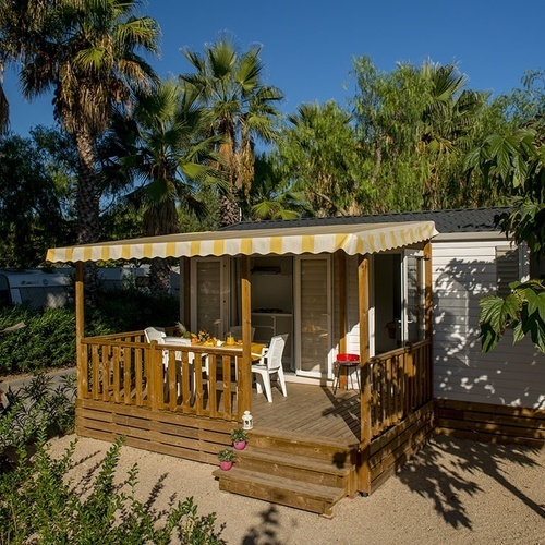 una casa móvil con una mesa y sillas en el porche