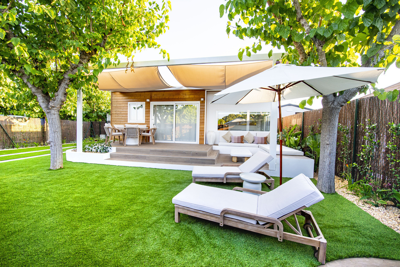 Espace extérieur luxueux d'un hôtel avec pelouse artificielle, transats, parasol et maisonnette pour une détente parfaite Creixell camping & family resort.