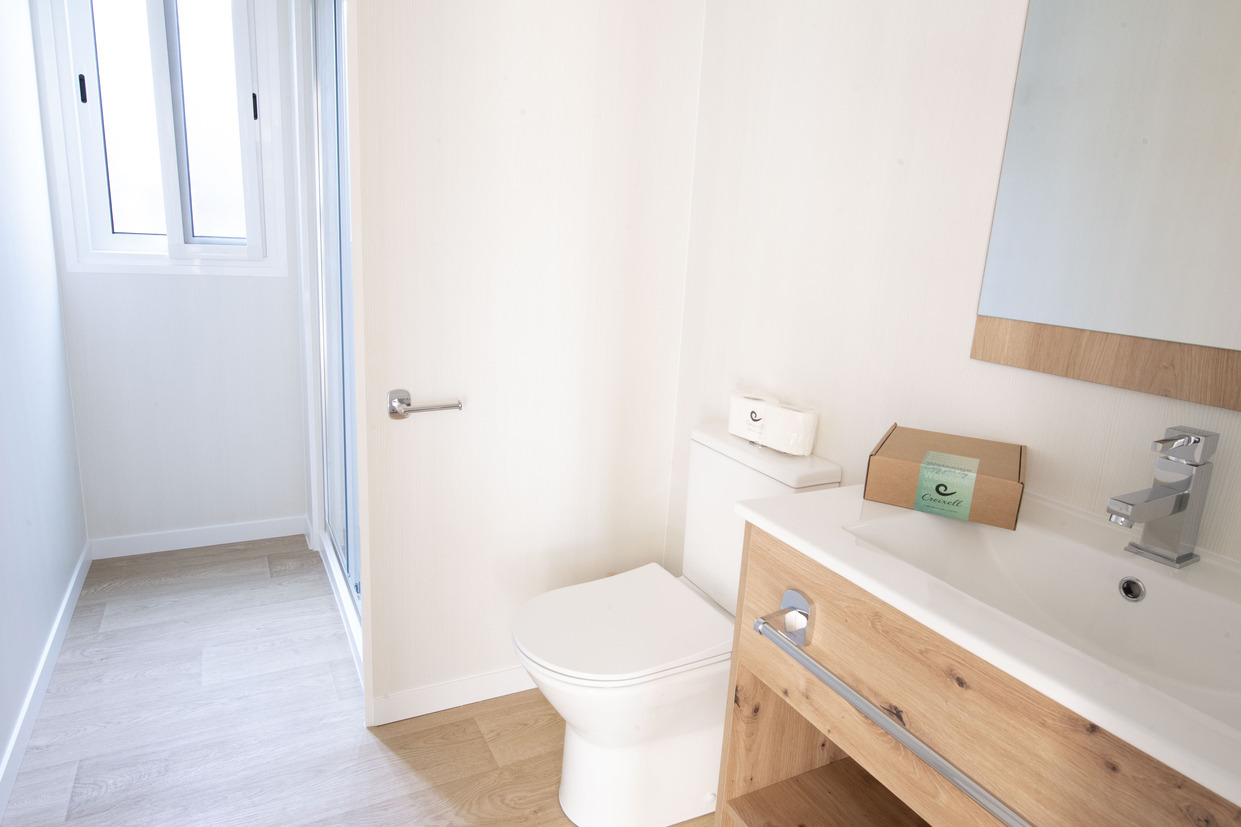 Salle de bain moderne avec douche, toilettes et lavabo en bois, idéale pour un séjour Creixell camping & family resort.