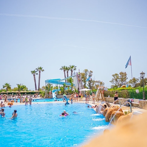 un grupo de personas nadando en una piscina con un tobogán en el fondo
