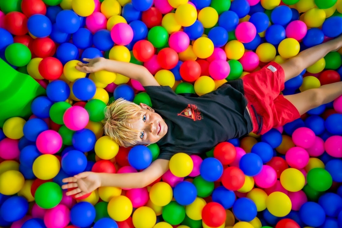 un niño acostado en un montón de bolas de colores