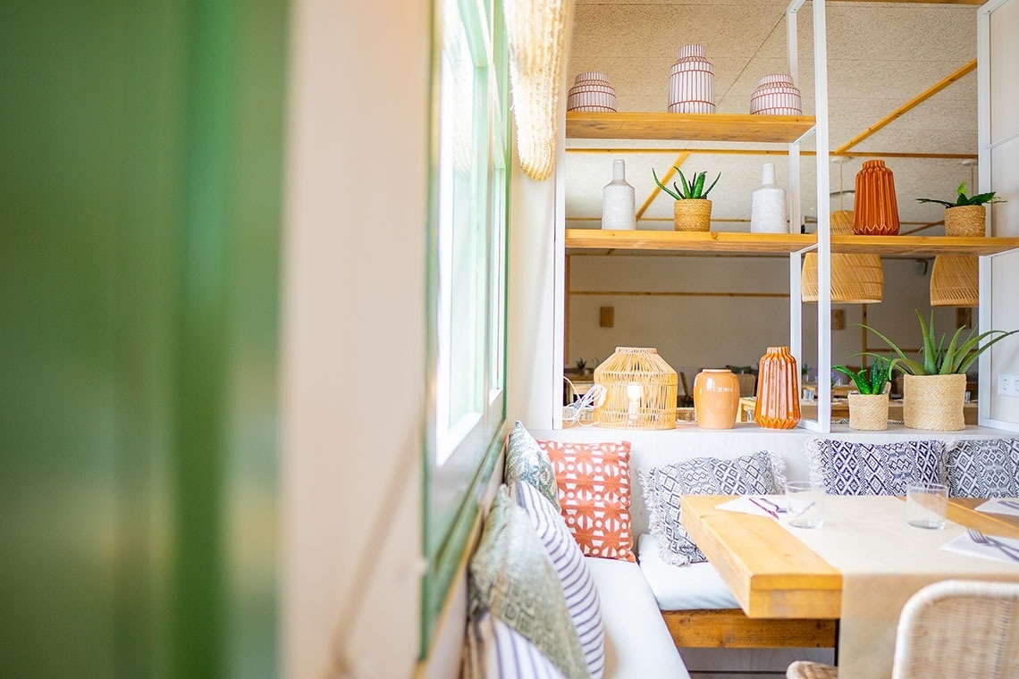 una mesa y un sofá en una habitación con plantas en los estantes