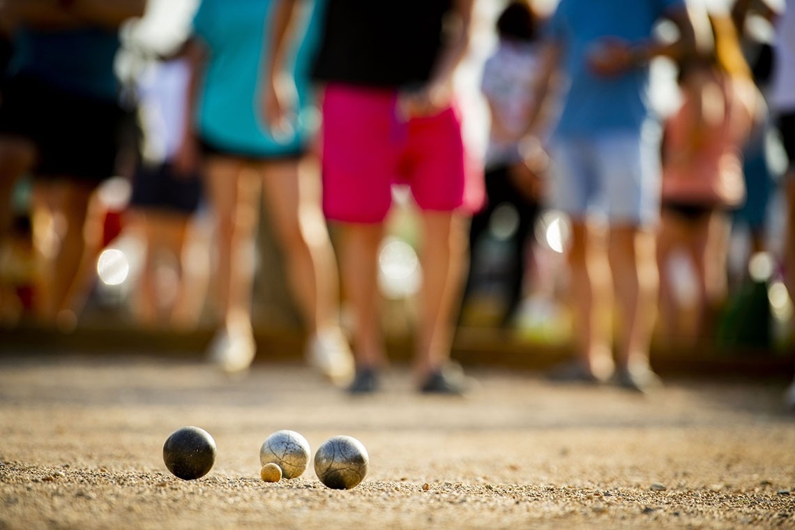 dos bolas de boliche están en el suelo con una multitud de personas en el fondo