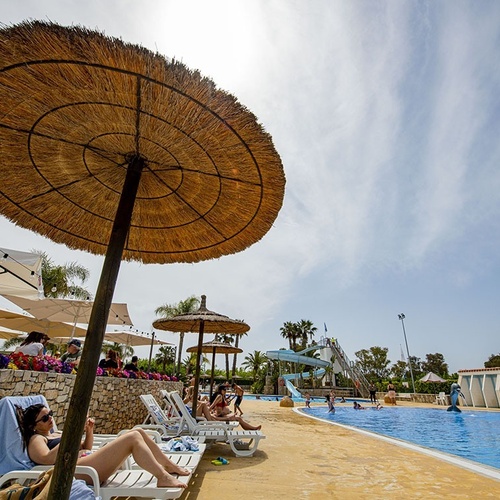 una mujer se sienta en una tumbona bajo un paraguas estrella damm