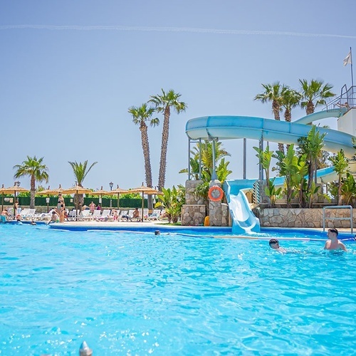 un grupo de personas nadando en una piscina con un tobogán en el fondo