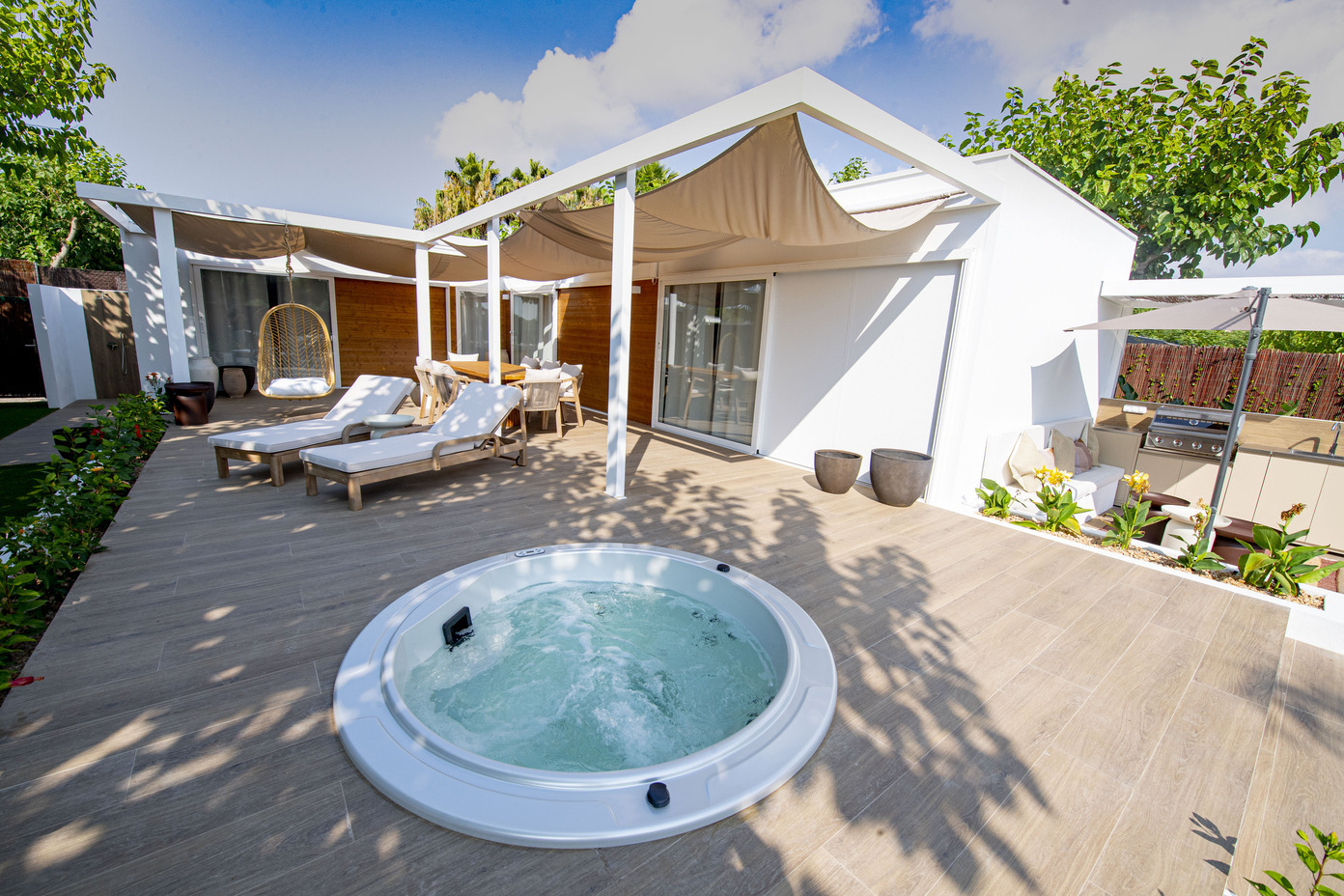 Jacuzzi extérieur et espace détente avec chaises longues et cuisine d'été, idéal pour un Creixell camping & family resort.