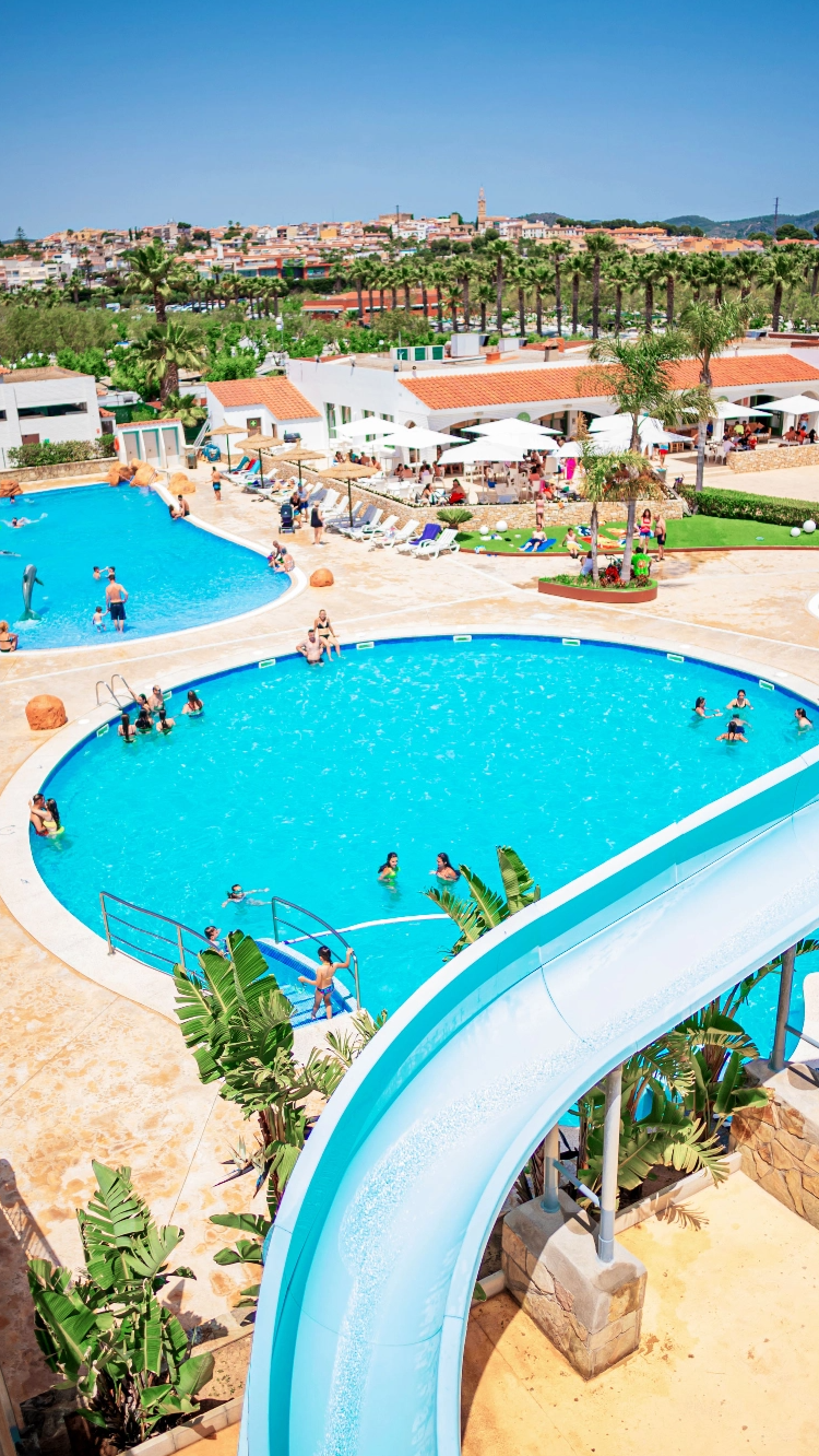 un grupo de personas nadando en una piscina junto a un tobogán