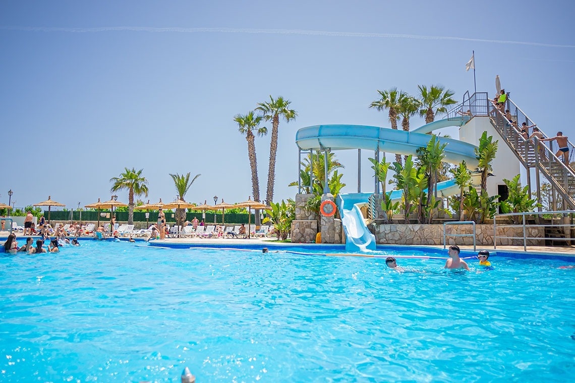 un niño se desliza por un tobogán de agua azul en una piscina