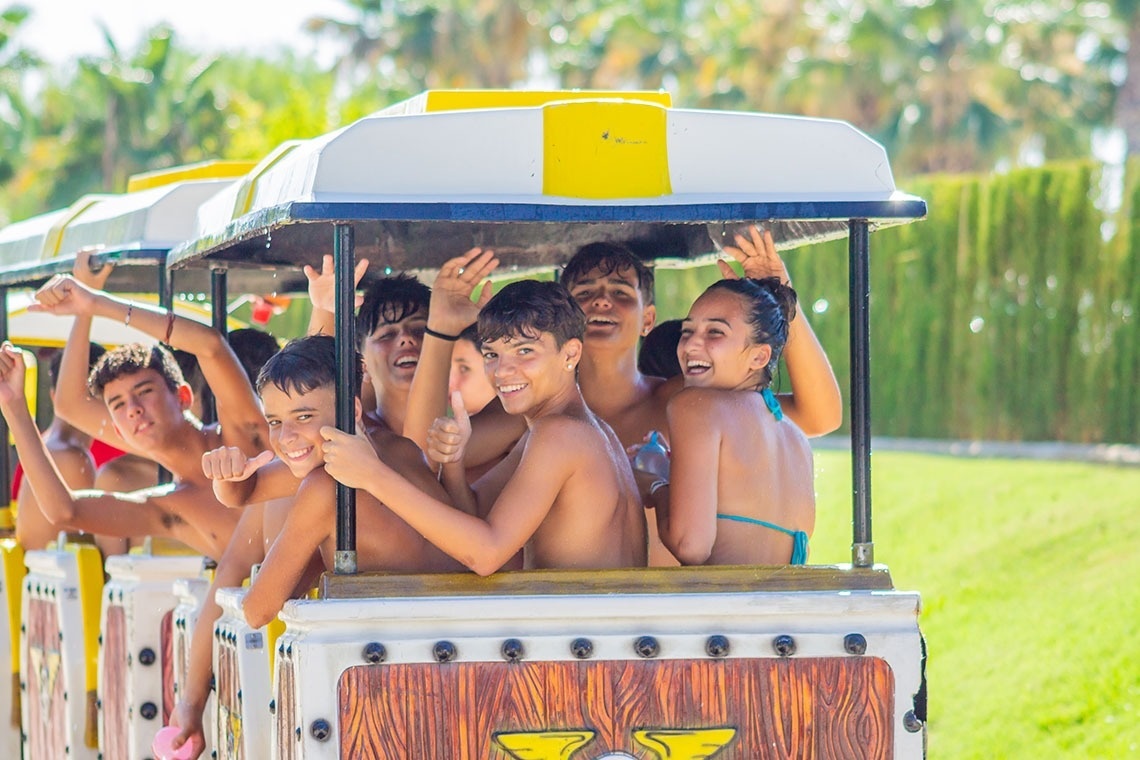 un grupo de niños y niñas están sentados en un tren y dando pulgares hacia arriba