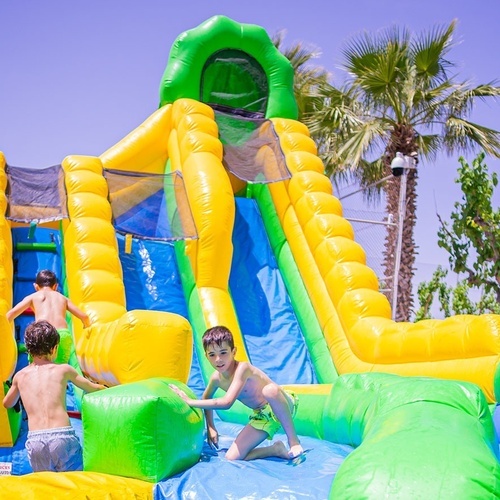 dos niños juegan en un tobogán inflable en un parque