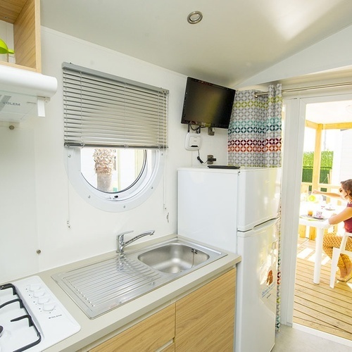 una mujer se sienta en una mesa en la cocina de una casa móvil