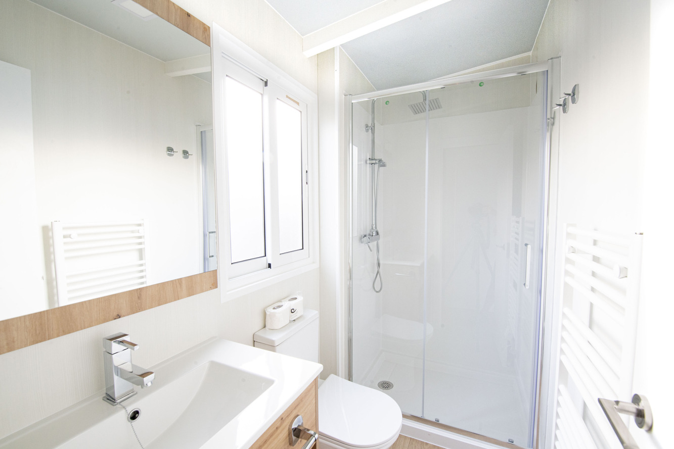 Salle de bain moderne avec douche vitrée, lavabo et toilette, idéale pour votre séjour Creixell camping & family resort.