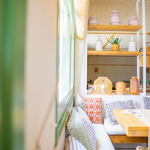 una mesa y un sofá en una habitación con plantas en los estantes