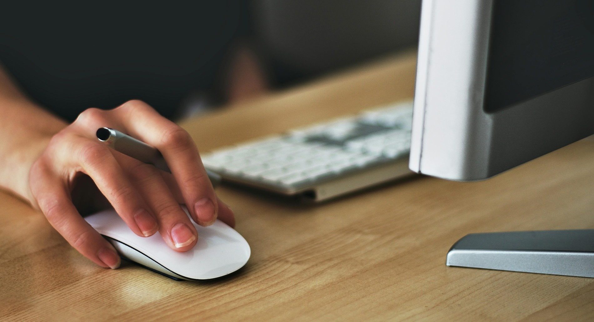 una persona sostiene un bolígrafo mientras usa un ratón de computadora