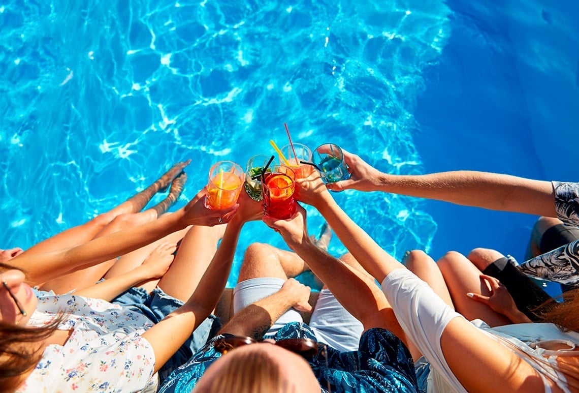 un grupo de personas se sienta en la piscina con bebidas en sus manos