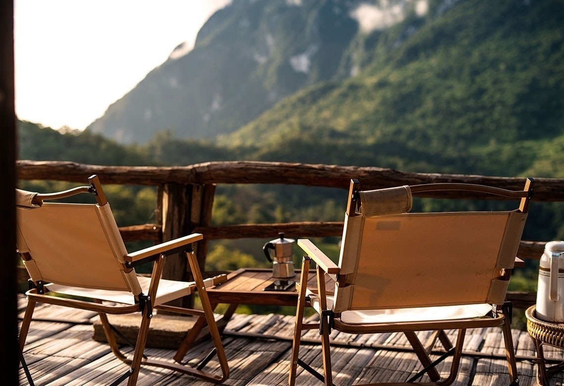 dos sillas y una mesa en un balcón con vistas a las montañas