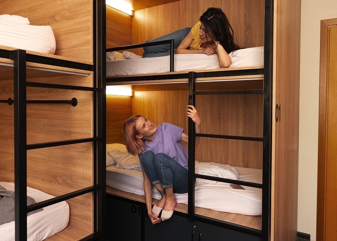 dos mujeres están sentadas en literas y una de ellas está subiendo una escalera