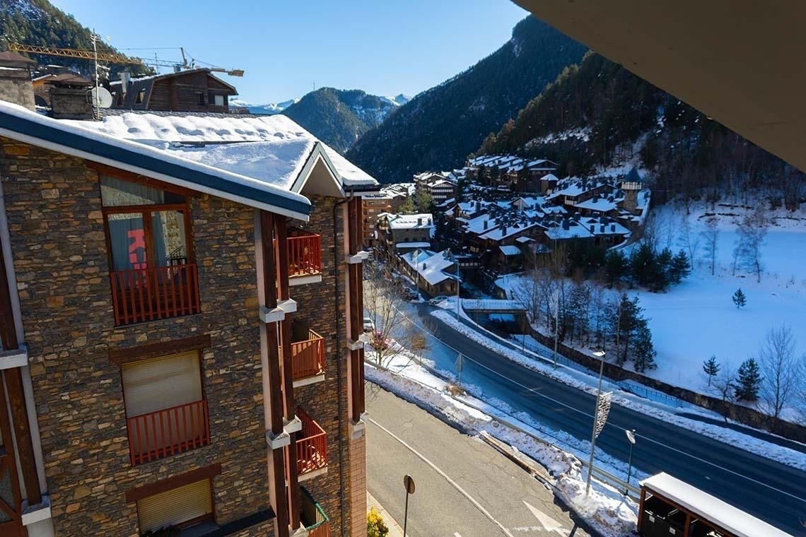 un edificio de piedra con balcones y una carretera cubierta de nieve