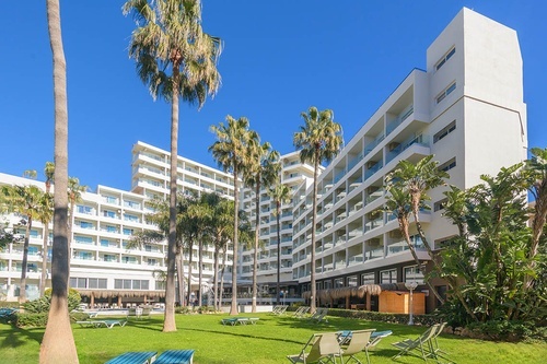 Hotel Parasol Torremolinos: Edificio moderno con palmeras y césped.