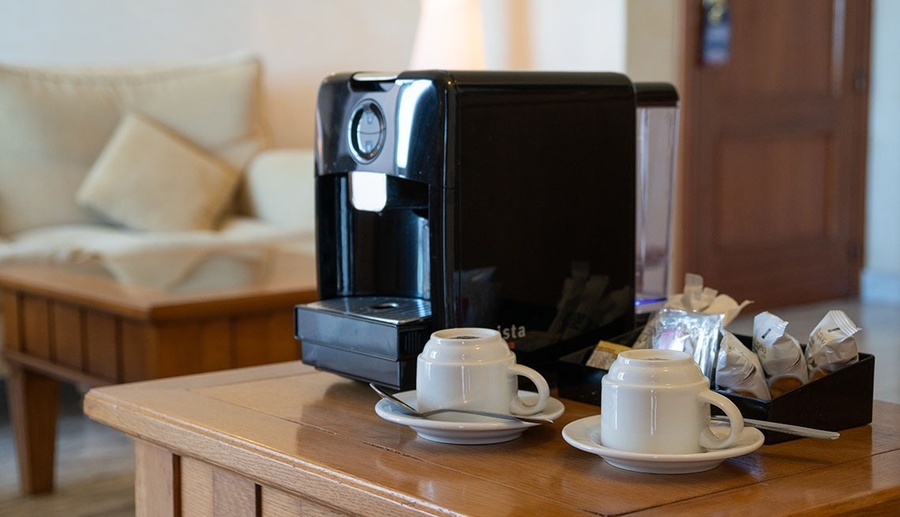 una máquina de café está sobre una mesa de madera junto a dos tazas de café