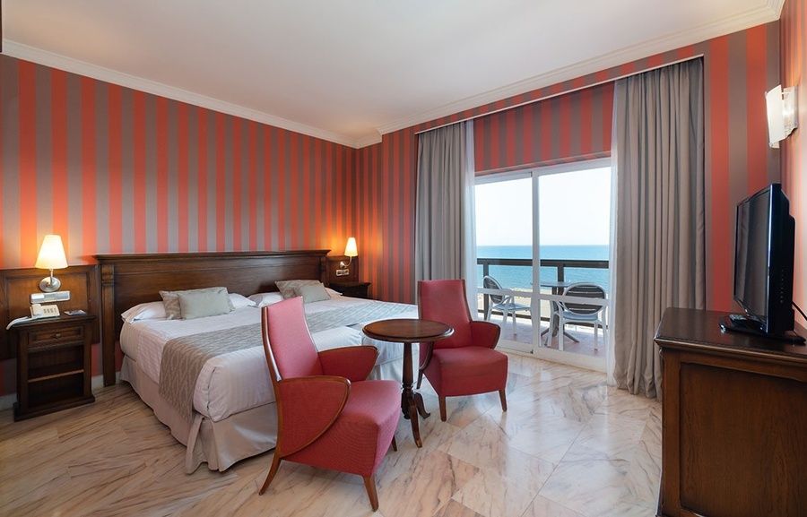 una habitación de hotel con una cama doble y dos sillas rojas