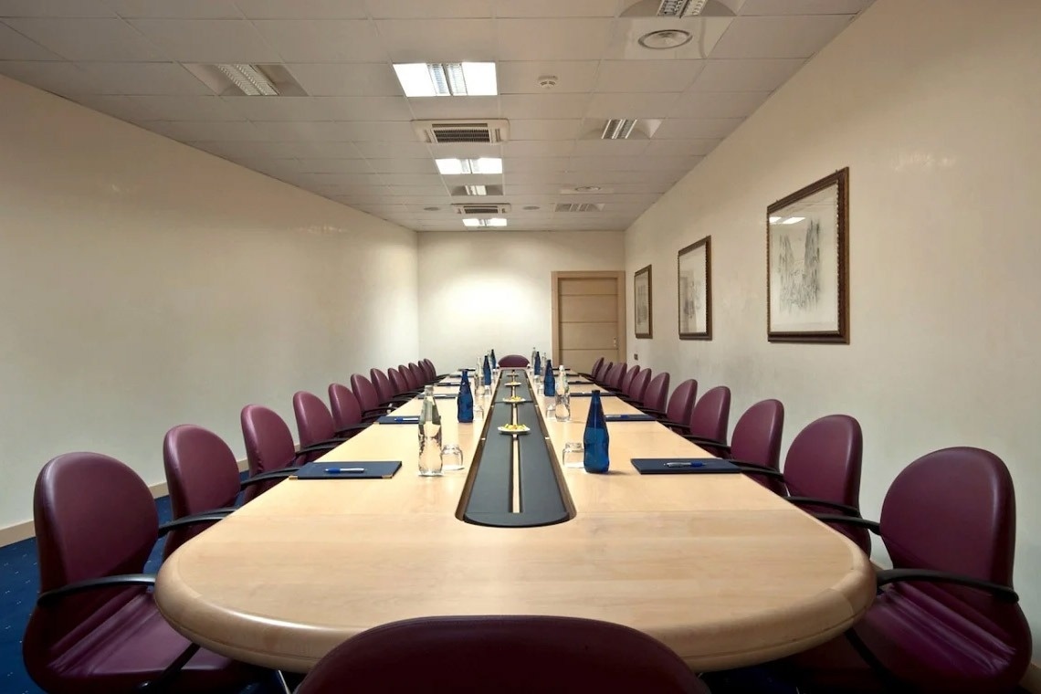 una sala conferenze con un lungo tavolo e sedie viola