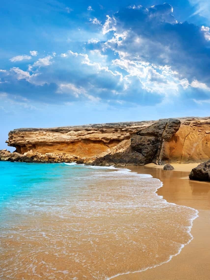 ein Strand mit einem felsigen Felsen im Hintergrund