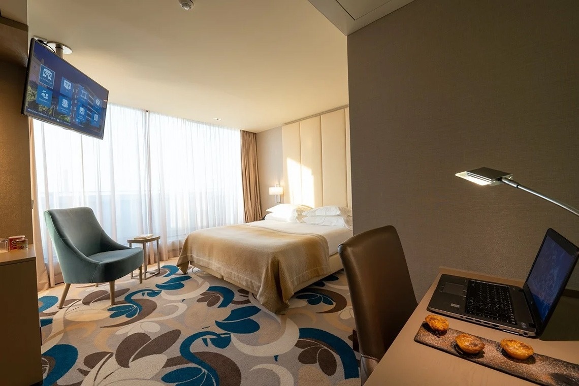 a hotel room with a large bed and a laptop on the desk