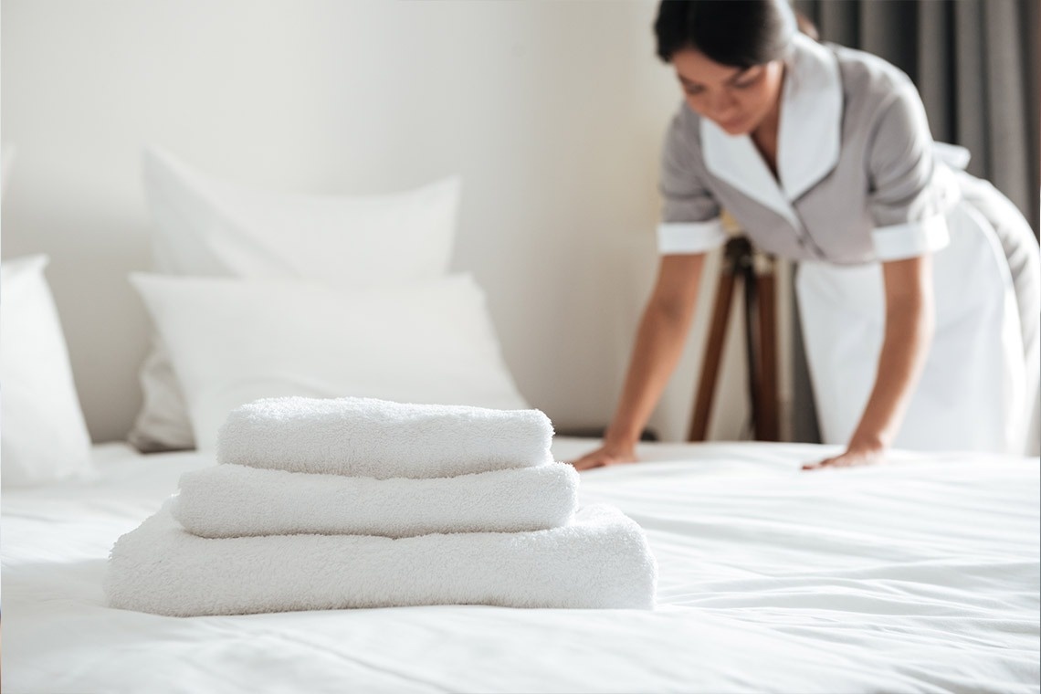 a maid is making a bed with white towels