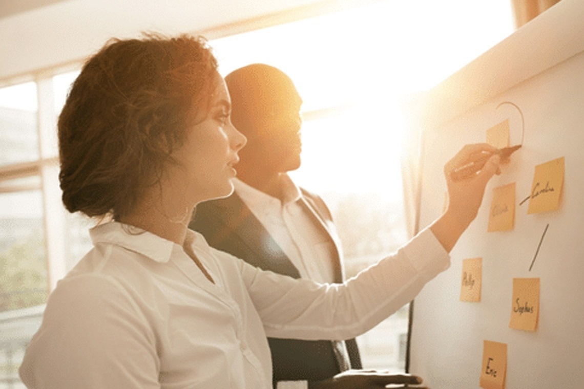 una donna sta scrivendo su una lavagna con un pennarello