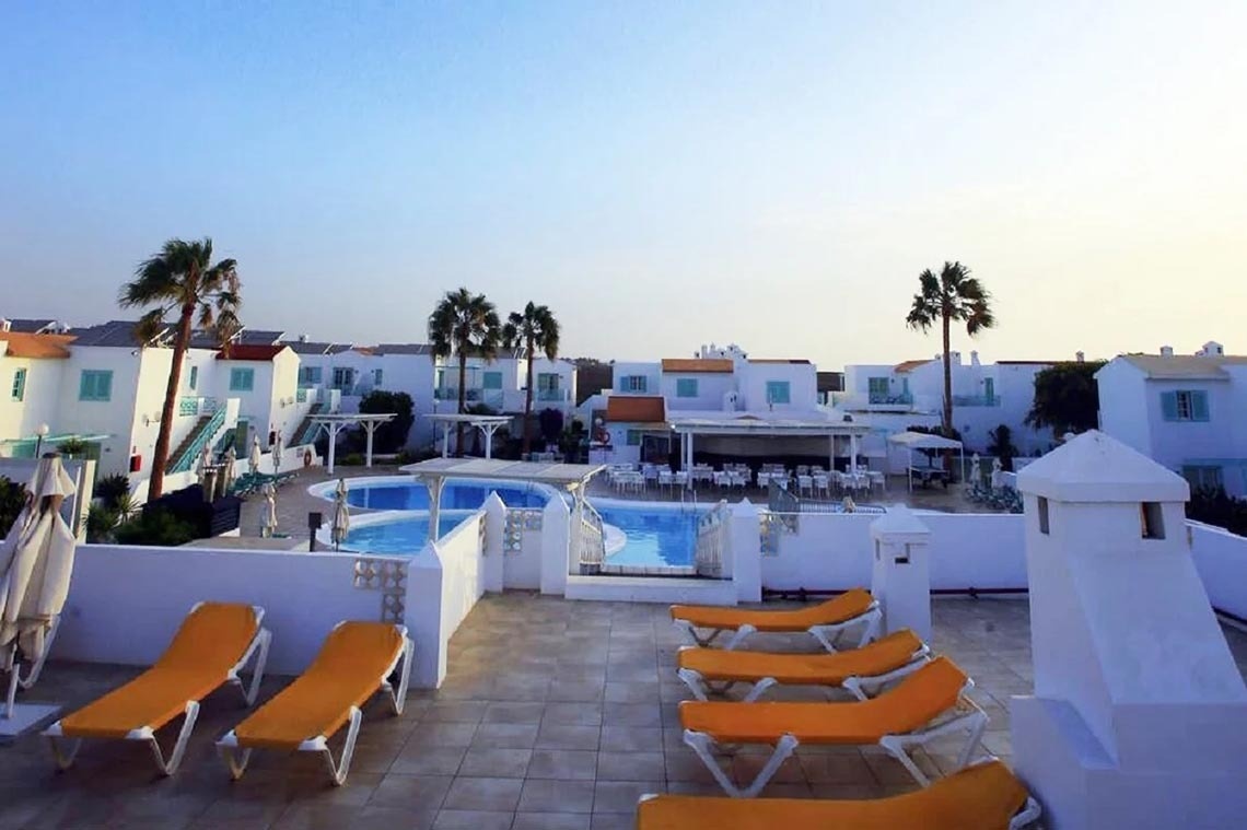 Liegestühle und Sonnenschirme stehen auf einer Terrasse neben einem Pool