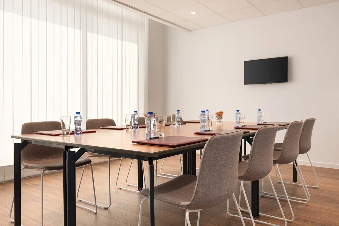 uma sala de conferências com mesas e cadeiras e garrafas de água