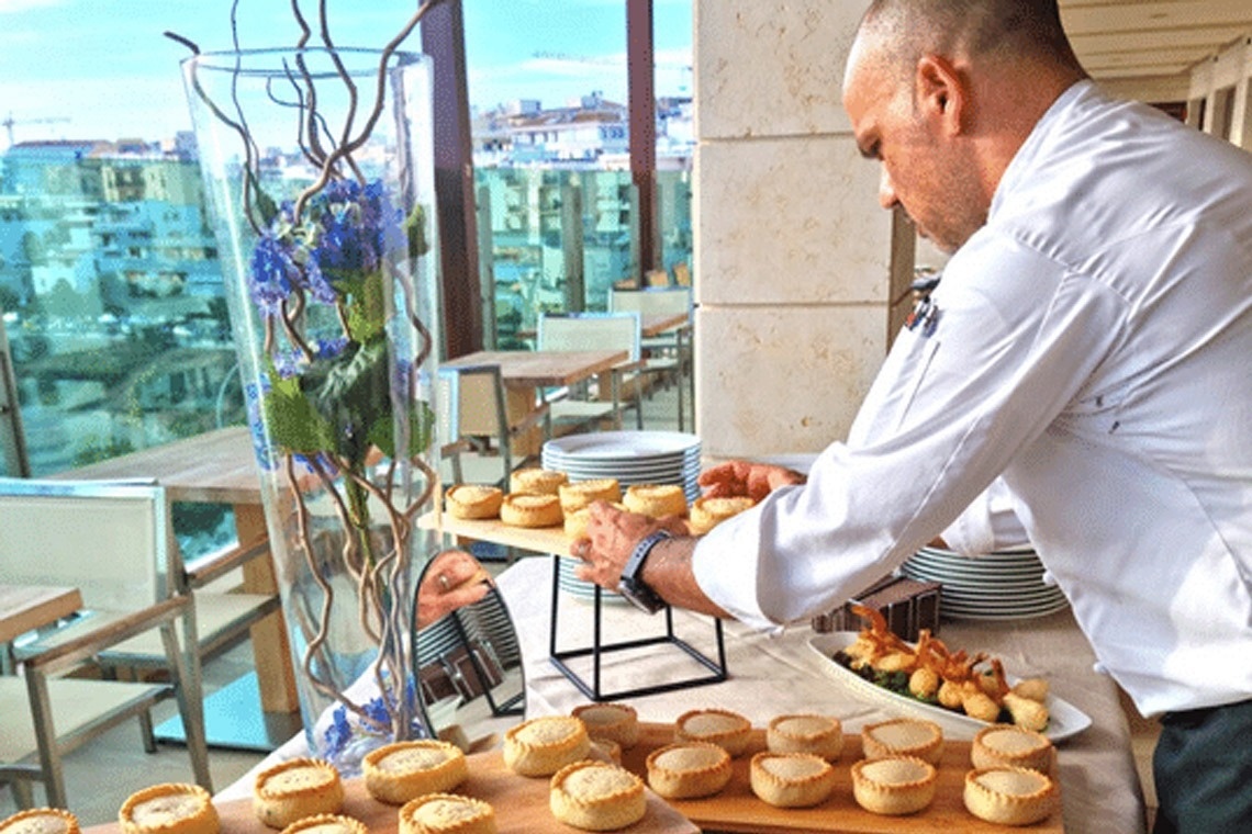 un uomo in piedi davanti a un tavolo pieno di pasticcini