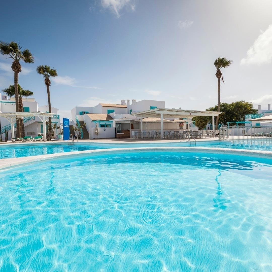 una grande piscina circondata da palme e un edificio bianco