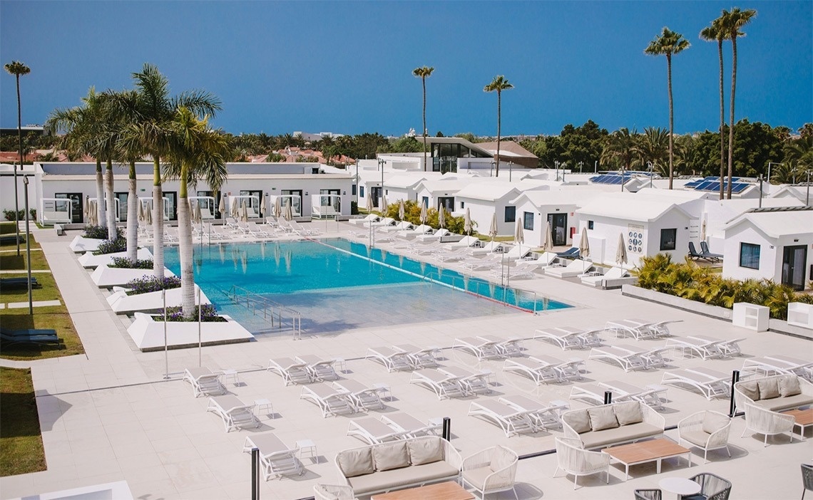 a large swimming pool surrounded by white chairs and tables