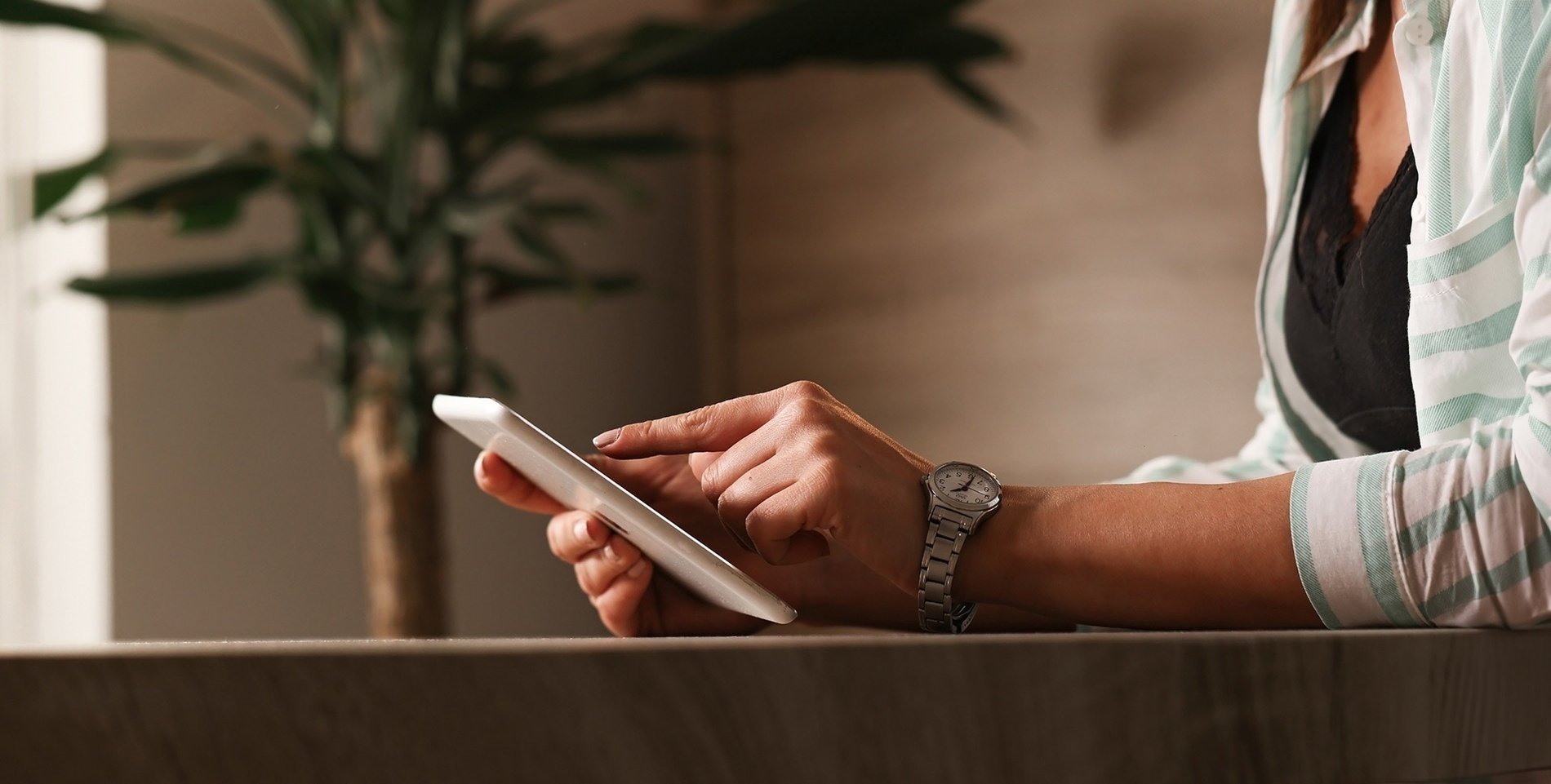 a woman wearing a watch is using a tablet