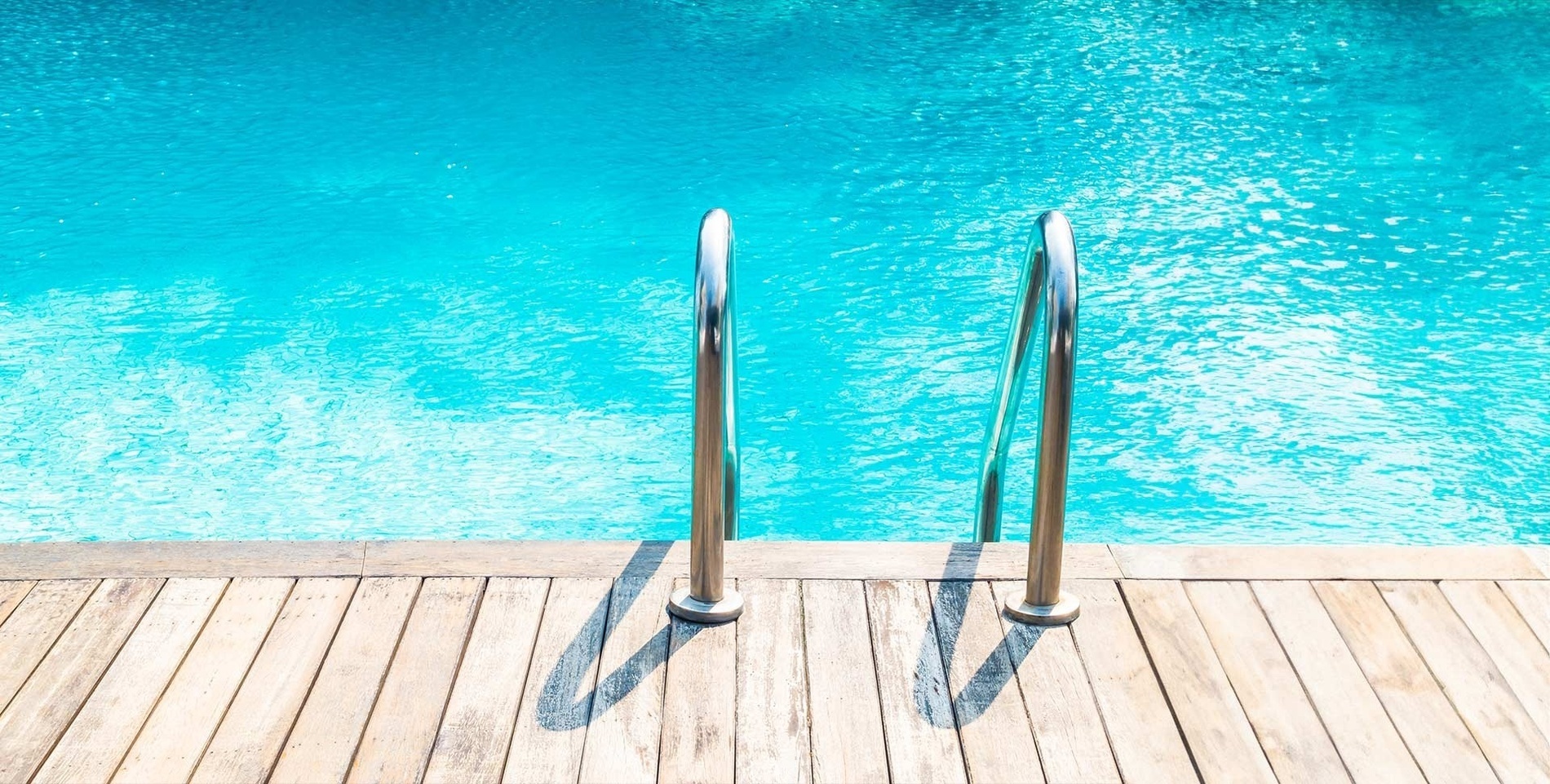 a wooden deck with stairs leading to a swimming pool