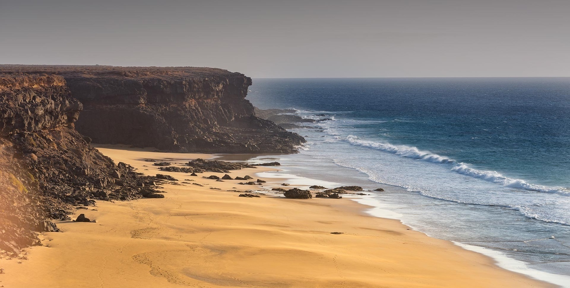 una playa de arena con un acantilado en el fondo